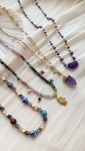 Λεπτομέρεια από boho κολιέ με αμέθυστο, χέρι Hamsa και κοχύλια σε λευκό μετάξι