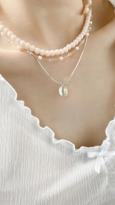 Detailed view of layered necklace with pink beads, silver chains and opal pendant