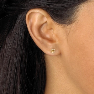Gros plan d'une boucle d'oreille minimaliste avec pierre ronde champagne et monture argent