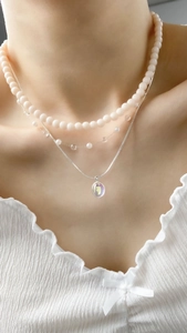 Close-up of three-layered necklace set with pink beads and iridescent pendant on model