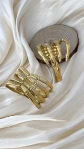 Close-up of golden gothic skull hand bracelets on silk background and wooden display