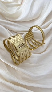 Detailed view of two gold skeleton hand hair claws on elegant beige silk fabric