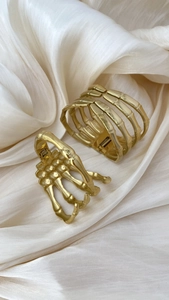 Detailed view of golden skeleton hand open bangles on elegant silk fabric backdrop