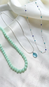 Detailed flat lay of luxury layered necklaces with green beads and blue stone pendants