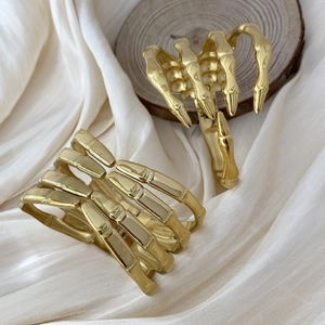 Polished gold skeleton hand hair claws for women displayed on elegant silk background