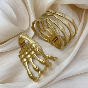 Gothic style golden skeleton hand bracelets with hinged design on beige silk fabric
