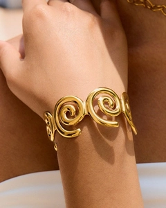 Primo piano di un bracciale a spirale dorato con design geometrico a vortice strutturato