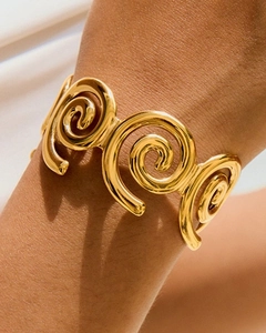 Dettaglio del bracciale a fascia dorato a spirale con finitura lucida e design aperto