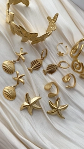 Collezione di gioielli con stelle marine dorate su sfondo di raso bianco