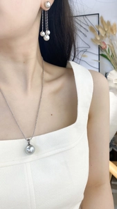 Detail of elegant silver-grey pearl necklace and matching drop earrings on a model