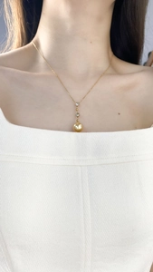 Detailed view of a gold pearl necklace with zircon accents on a female model