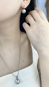 Detailed view of silver-grey pearl necklace and earrings set on a model with metallic luster