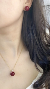 Detail of red bead jewelry set with gold necklace and matching stud earrings on model