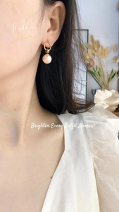 Detail of pink pearl drop earrings with gold hoops worn by a model for elegant style