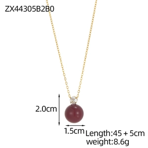 Detail of a minimalist gold chain necklace with a clear zircon and burgundy bead pendant