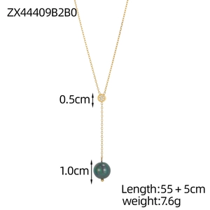 Detail of Y-shaped gold necklace featuring a zircon ring and a green bead pendant