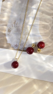 Macro view of French luxury red pearl necklace and earrings with gold metal accents