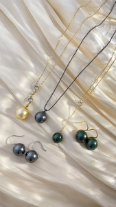 Detail of luxury pearl necklaces and earrings in gold, grey and green on champagne satin