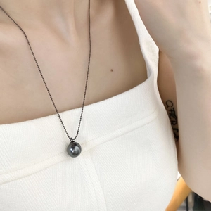 Elegant black pearl pendant necklace with dark beaded chain on female model