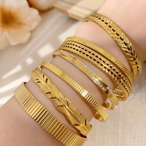 Detail of gold-plated bracelet set featuring feather design and zircon stones