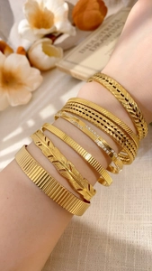 Detailed stack of gold leaf and feather bangle bracelets with cubic zirconia accents