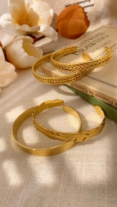 Detail of four vintage gold open bracelets with textured feather and wheat leaf patterns