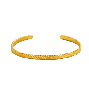 Macro shot of gold cuff bracelet featuring fine diagonal textures and adjustable C-shape