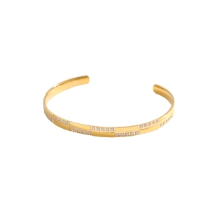 Detail of adjustable C-shaped gold cuff bracelet with double row of inset white zircons