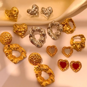 Vintage gold and silver hammered heart earrings and rings on smooth satin background
