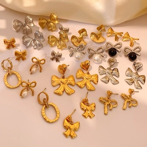 Elegant bow and pearl earrings in gold and silver finishes on a silk background