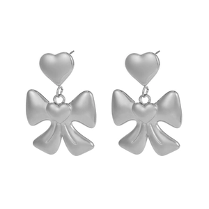 Close-up of silver bow earrings with heart studs in a high-polished metallic finish