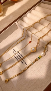 Detail of gold jewelry set with pearls and gemstones in a beige velvet gift box