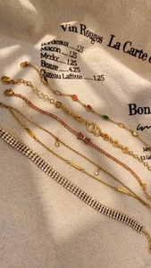 Detailed close-up of multiple gold adjustable bracelets with colorful crystals and charms