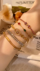 Detailed view of a five-piece gold bracelet set with pink crystals and butterfly charms