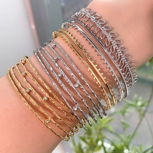 Dettaglio di bracciali argentati a strati con trama a foglia e finiture pavé intrecciate