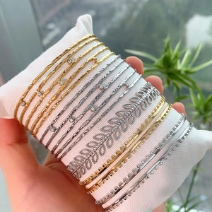 Dettaglio di bracciali multistrato argentati con foglie e texture metalliche