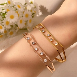 Dettaglio di bracciali a doppio strato con cornici geometriche cave e zirconi incastonati