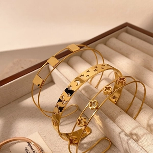 Eleganti bracciali dorati con stelle, lune e quadrifogli traforati in scatola di velluto