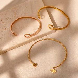 Dettaglio di bracciali geometrici in oro rosa su supporto in pietra dallo stile minimal