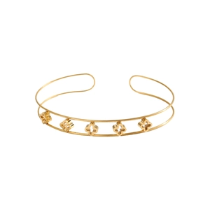 Dettaglio di un bracciale rigido dorato a due strati con cinque quadrifogli traforati