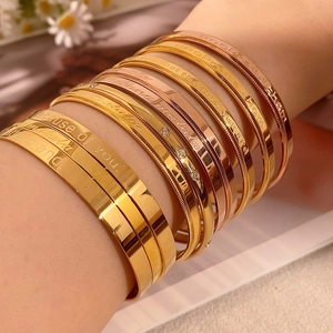 Close-up of stacked gold and rose gold bangles with inspirational engraved quotes