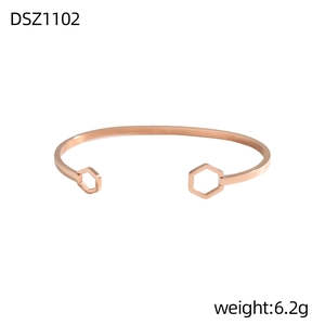 Dettaglio di un bracciale rigido oro rosa con ciondoli esagonali cavi e finitura lucida
