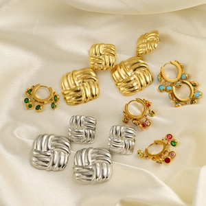 Colorful gemstone earrings and gold woven studs set on elegant white silk background
