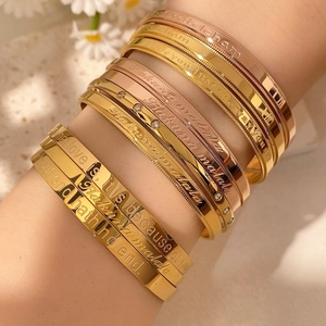 Detailed view of stacked gold and silver bracelets with elegant Hakuna Matata engraving