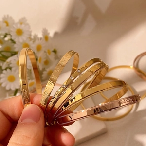 Detail of gold and rose gold metal bangles with engravings and cubic zirconia accents