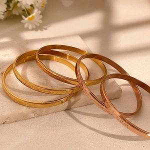Polished gold and rose gold bangles with emotional engraving and beaded edge details