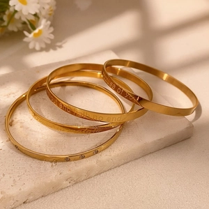 Elegant gold bangle set with inspirational engravings and crystals on white stone