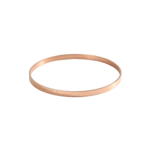 Macro shot of rose gold bangle featuring Hakuna Matata engraving on polished metal