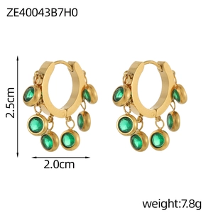 Detail view of gold hoop earrings featuring five vibrant green gemstone pendants