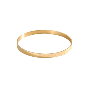 Detail view of gold bangle featuring smooth metallic luster and elegant quote engraving